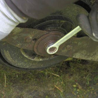 Slipe gressklipper kniv: Løsne boltene som holder kniven Slipe gressklipper kniv: Løsne boltene som holder kniven